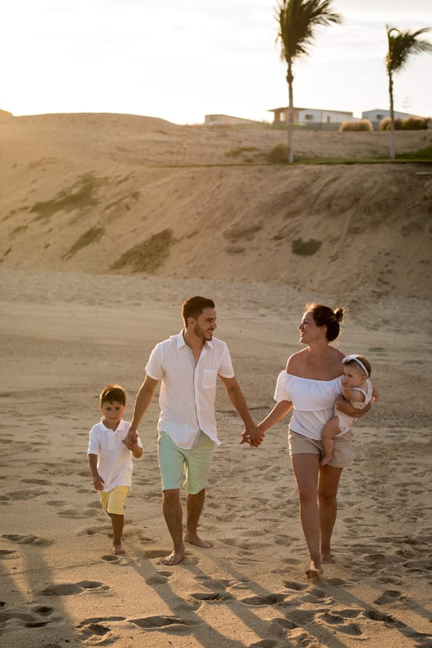 Familia caminando en la playa al atardecer